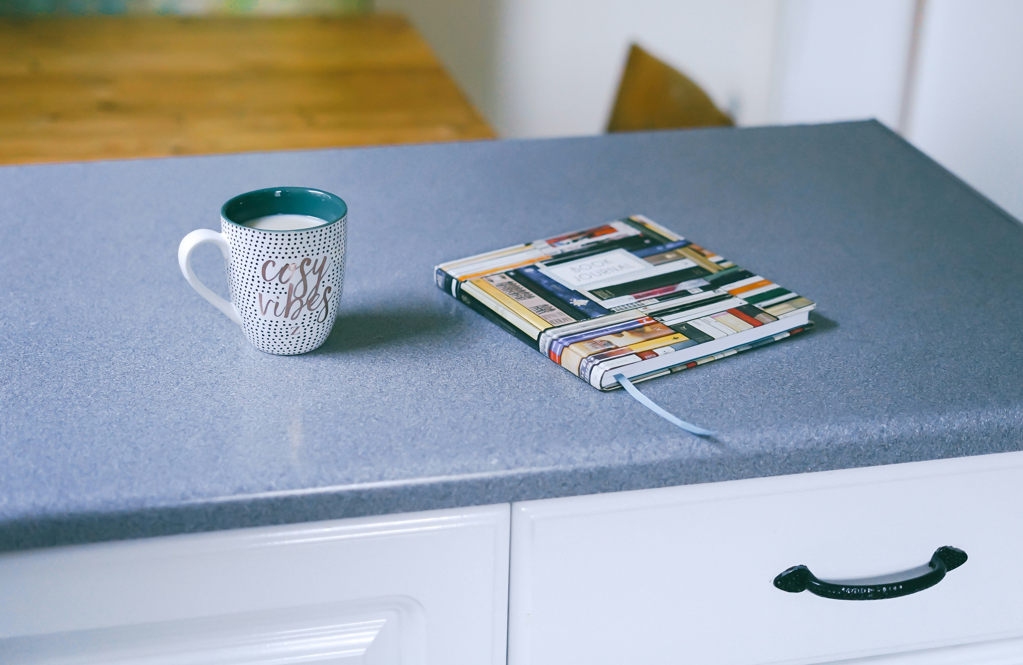 gray and white ceramic mug beside multicolored covered book